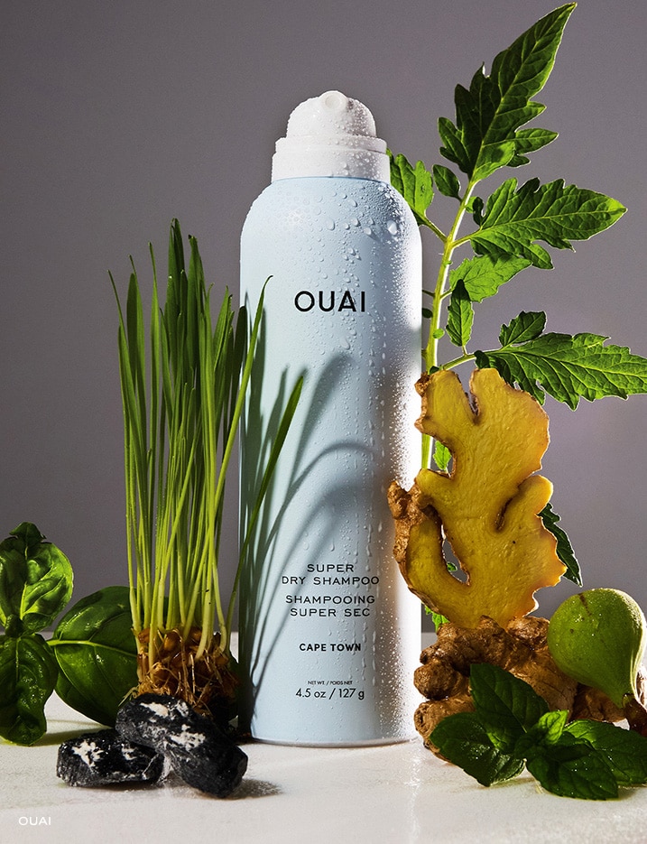 Bottle of Ouai Super Dry Shampoo surrounded by fresh ingredients.